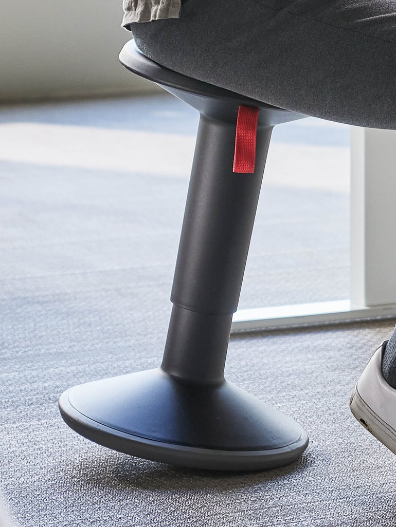 Balanspall med svart stolben och röd rem, designad för kontorsbruk.