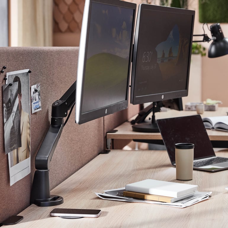 Skrivbord med två datorer och en kopp kaffe, lämpligt för en kontorsarbetsplats.