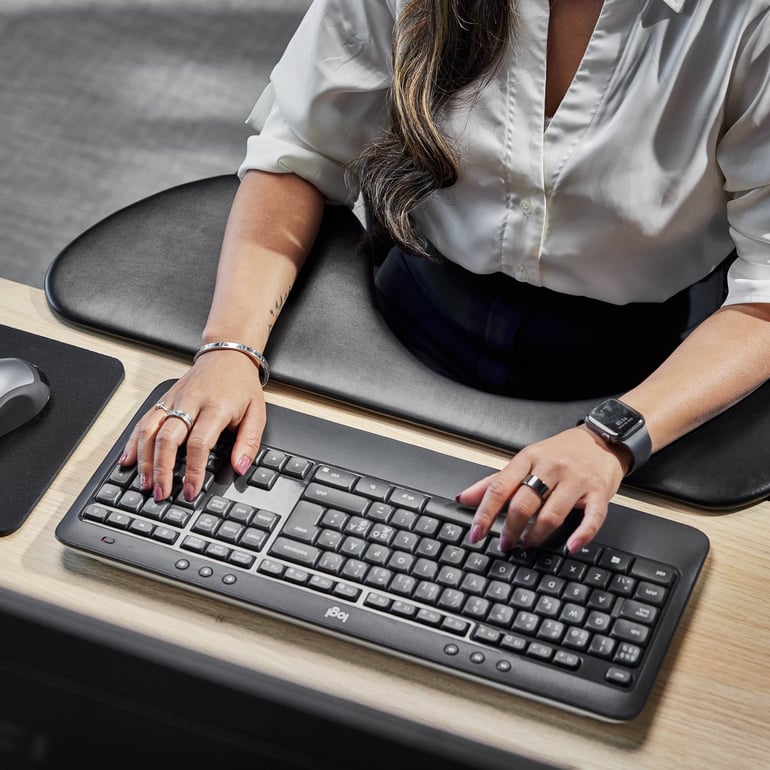 Person som skriver på ett datortangentbord med en mus i närheten i en inomhusmiljö.