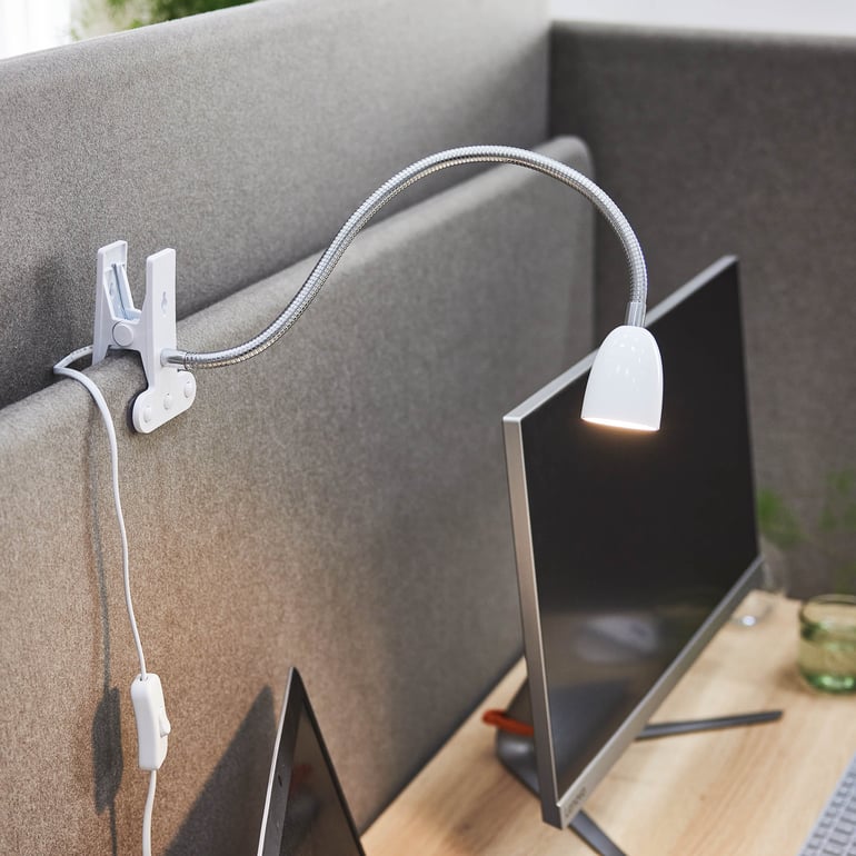 Desk lamp mounted on a desk screen, providing focused lighting in an office environment.