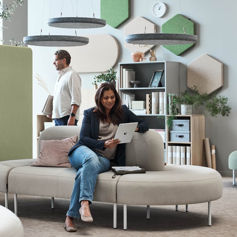 Person som sitter på en soffa i en loungemiljö, med en surfplatta i knät.