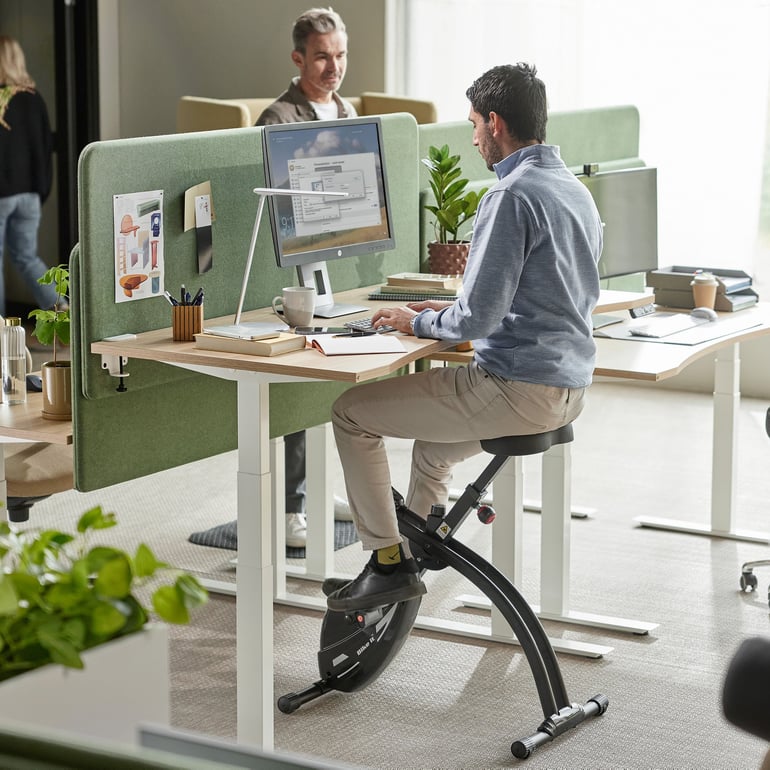 Person som sitter på en skrivbordscykel vid ett höj och sänkbart skrivbord