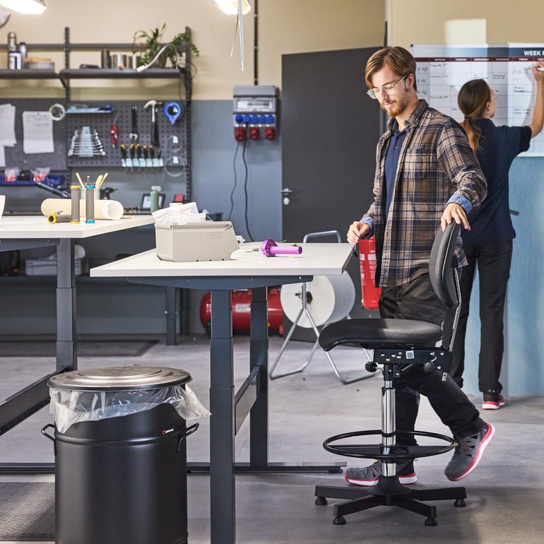 a person about to sit on his ergonomic factory chair in a workshop environment