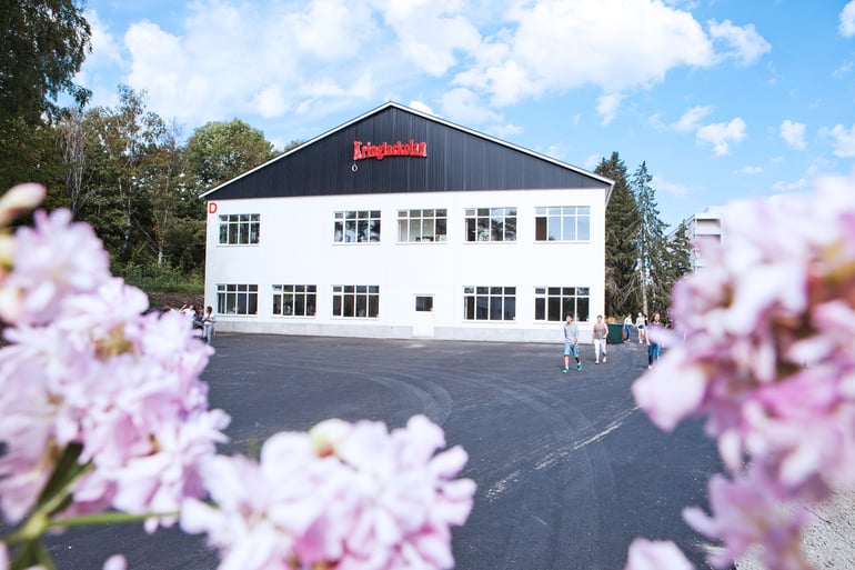 Et billede af Kringlaskolan med lyserøde blomster i forgrunden 