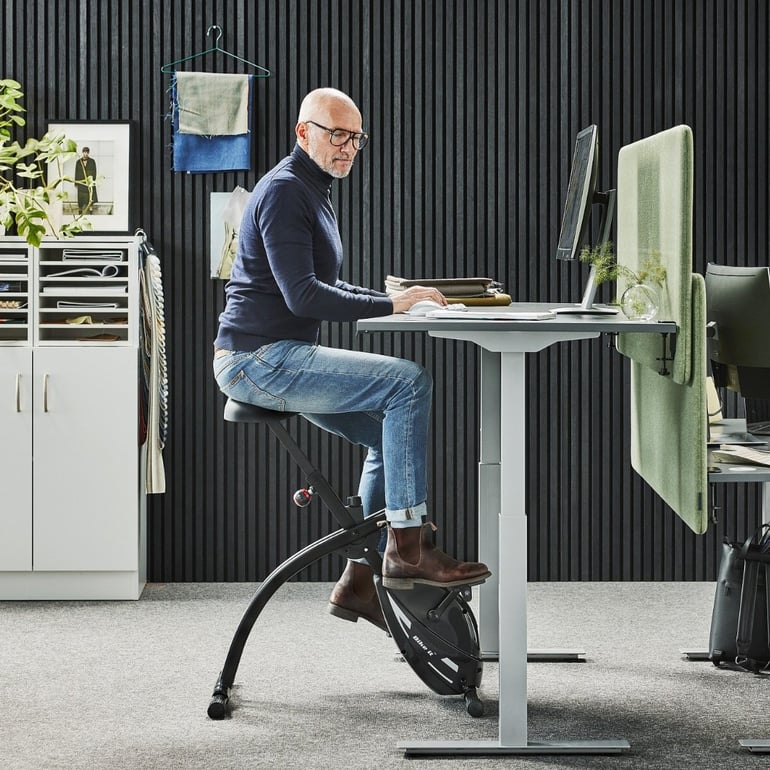 Muž v kanceláři na stolním rotopedu