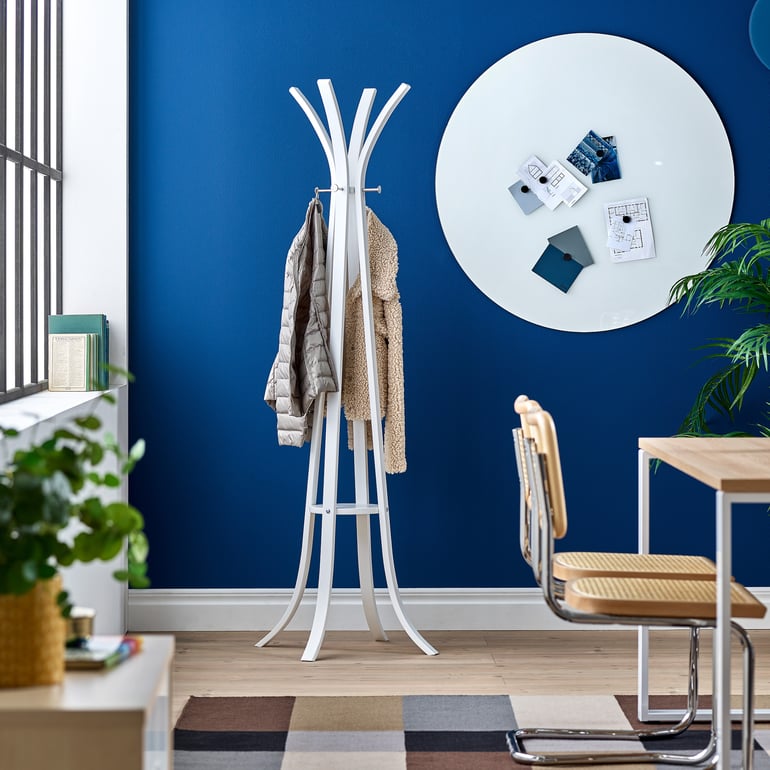 a MILLER wooden coat stand with height hooks by AJproducts against a blue wall with acoustic panels attached to it