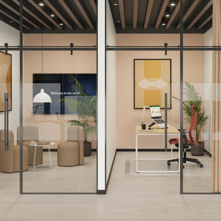 The image shows a modern office space divided into two glass-walled sections. On the left, there is a cosy seating area with neutral-toned pouffes, a small table, and indoor plants. A screen on the wall displays a message reading, "Welcome to the room." On the right, there is a minimalist workstation featuring a sleek desk, a red ergonomic chair, and a computer. The wall behind the desk displays abstract artwork in warm yellow and white tones, with additional plants adding a touch of greenery. The design emphasises an open, bright, and inviting workspace.