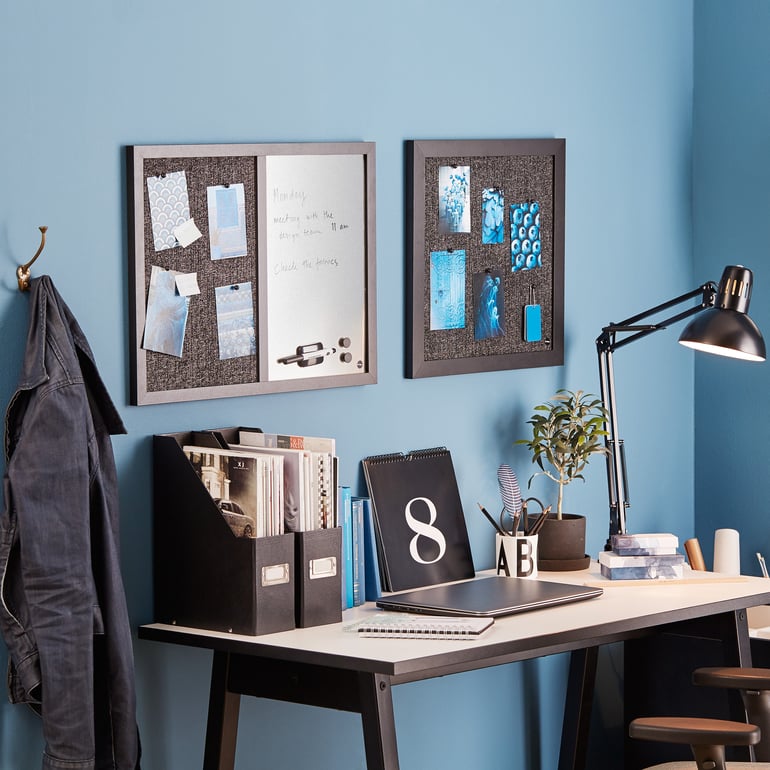 Two sleek, textured bulletin boards over a desk against a blue wall
