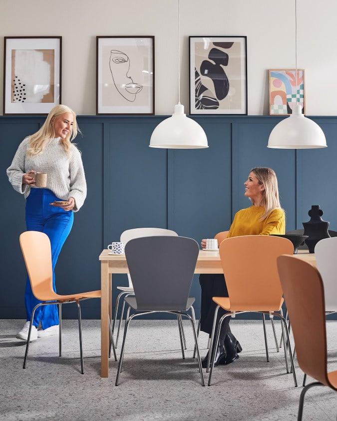 To kvinder i en kantine, der snakker over en kop kaffe