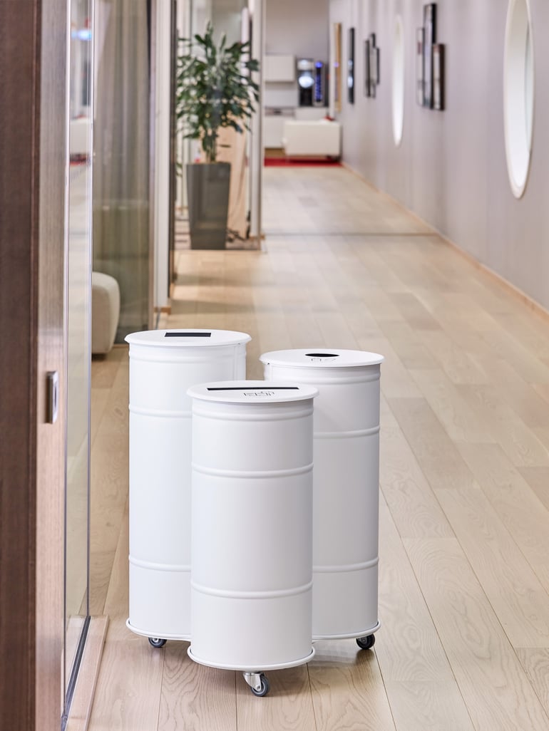 Three round waste containers in different heights on wheels with differently shaped openings