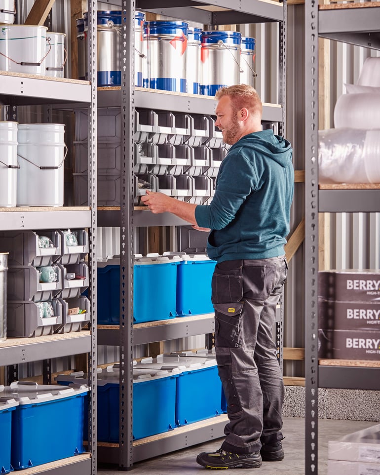 Warehouse workers pull plastic trays out of racks