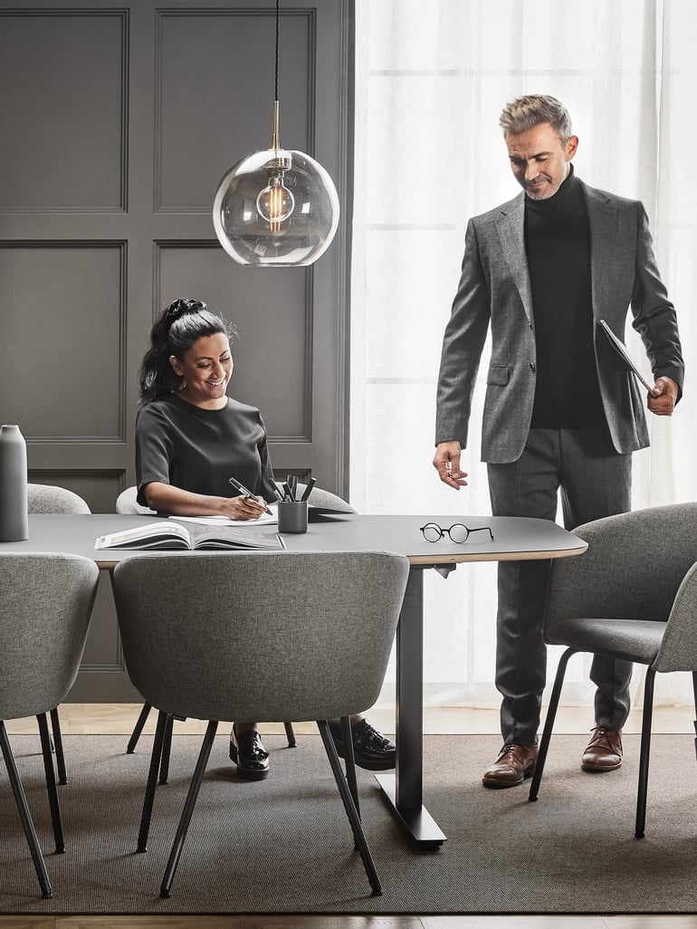 People preparing for a meeting in a conference room with a meeting table and chairs