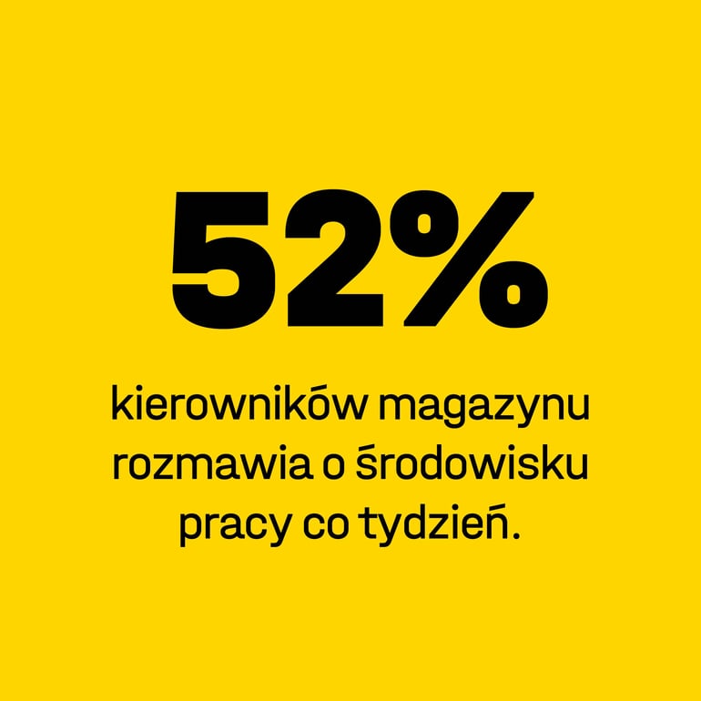 Dwie osoby siedzą na krzesłach biurowych przy biurkach i rozmawiają ze sobą