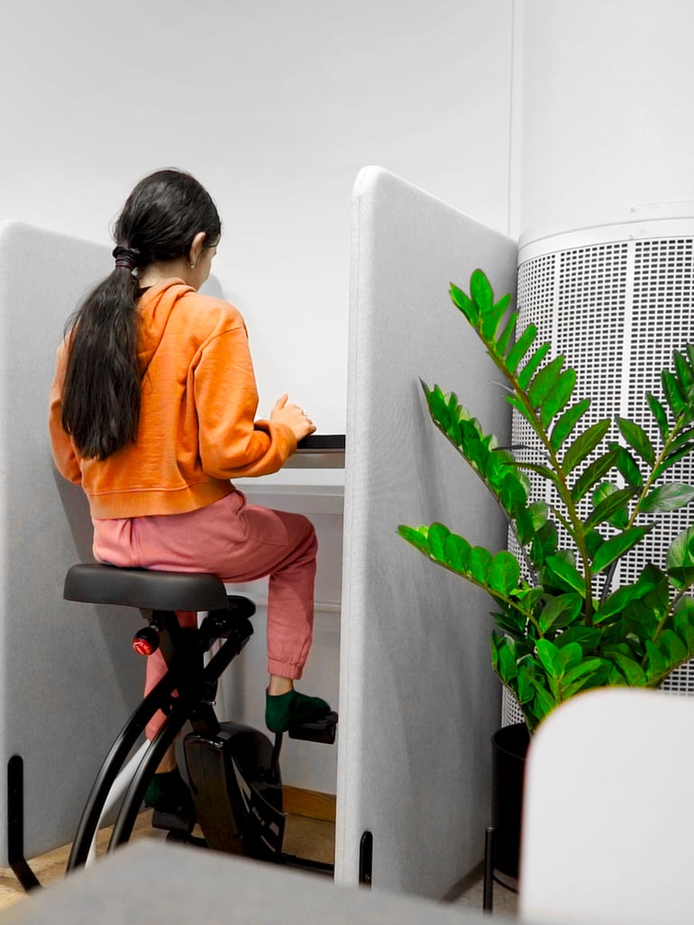 Student cycling on a desk bike while working