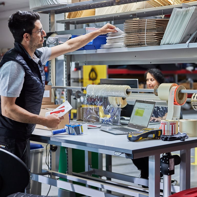 Muž ve skladu u balicího stolu