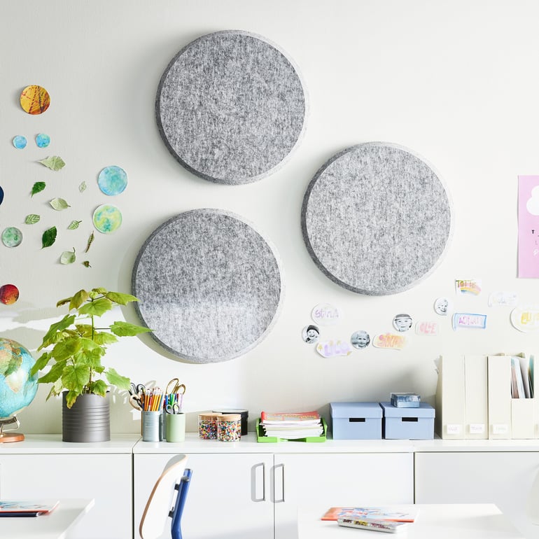 a classroom wall decorated with three large, round, gray sound absorber felt wall panels.