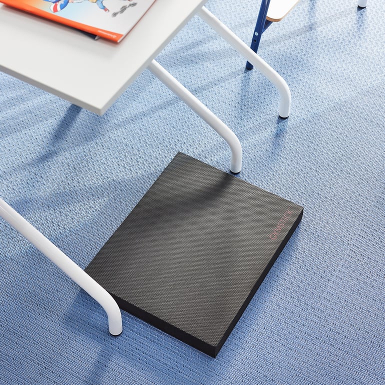 a standing desk mat placed on the floor under a school desk