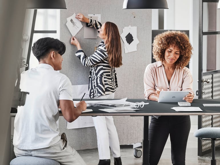 One person is sitting and one person is standing at a raised and lowered conference table.