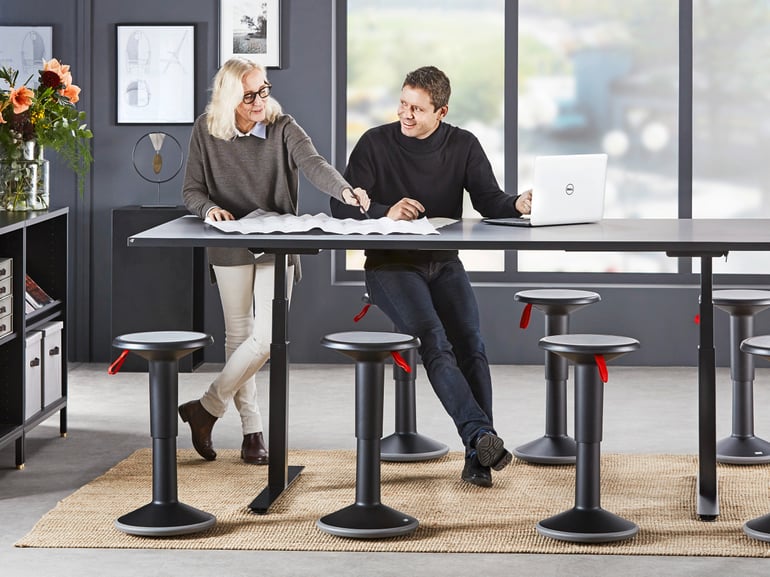 Two people stand at a raised and lowered conference table
