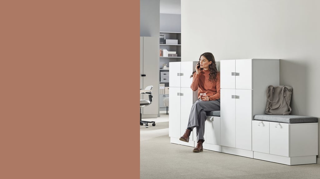 Woman sitting on a bench seat between storage cabinets