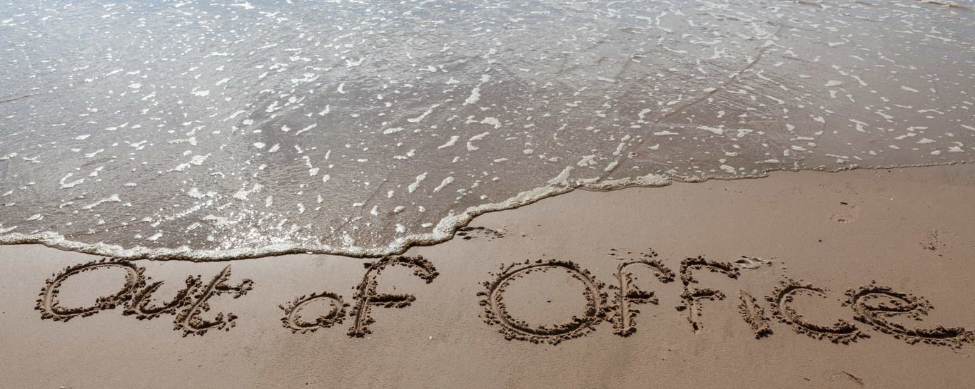 Out of office skrevet i sandet på en strand