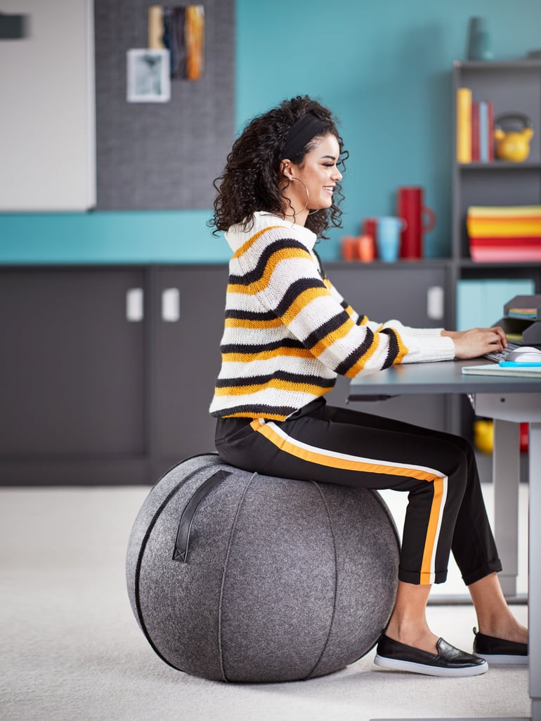 En person sidder ved et skrivebord på en balancebold