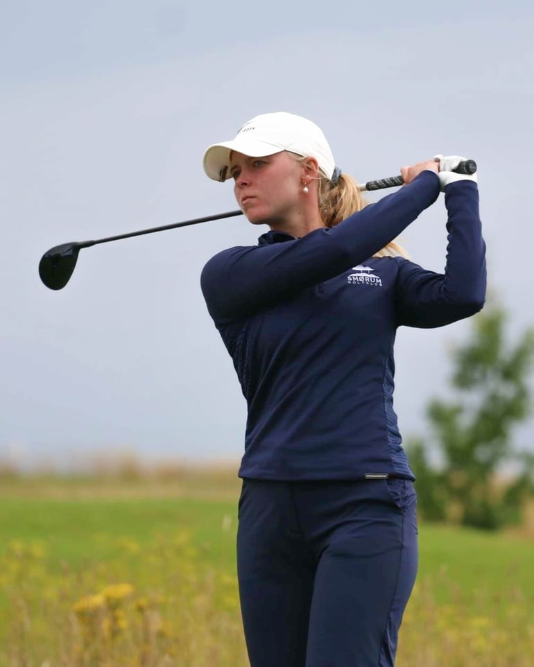 Natacha Høst Husted står afventende med sin golfkølle bag nakken lige efter et slag