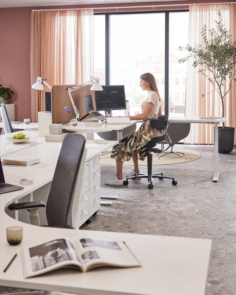 En kvinde sidder ved et hjørneskrivebord og arbejder
