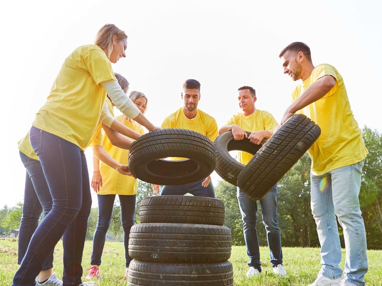 Kolleger er til teambuilding hvor de stabler dæk udendørs iført gule t-shirts