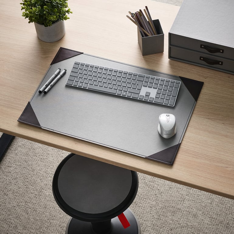 Et skrivebord med skriveunderlag, penneholder og andre ting til skrivebordet