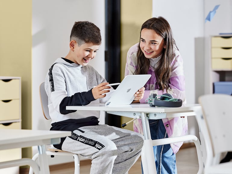 To børn kigger på et papir ved et skolebord