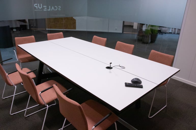 Hvitt møteromsbord med plommefargede konferansestoler