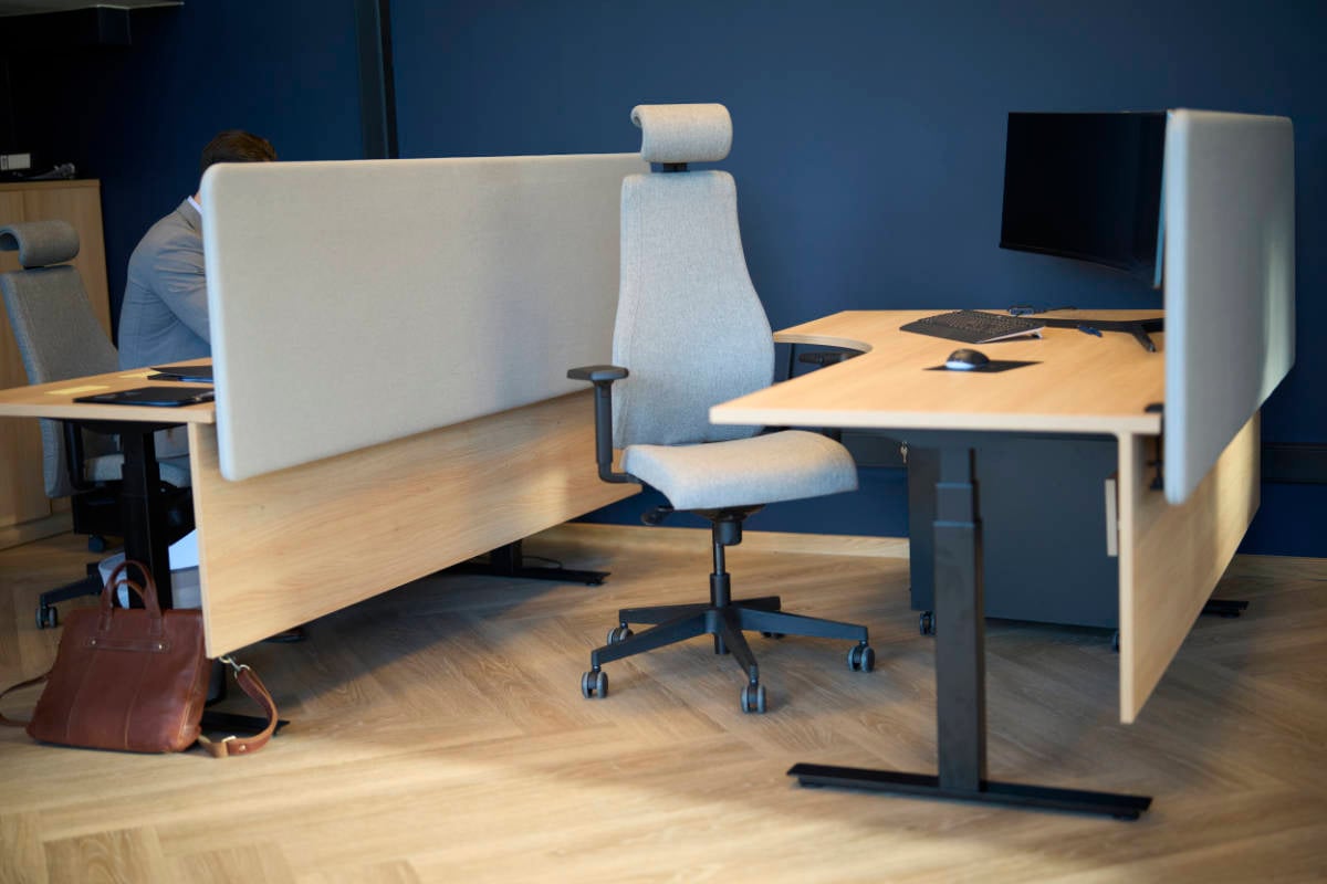 Grå kontorstol og skrivebord med bordskjerm