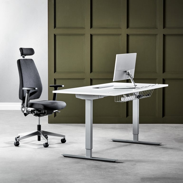 Electric height adjustable desk with white worktop and a black office chair