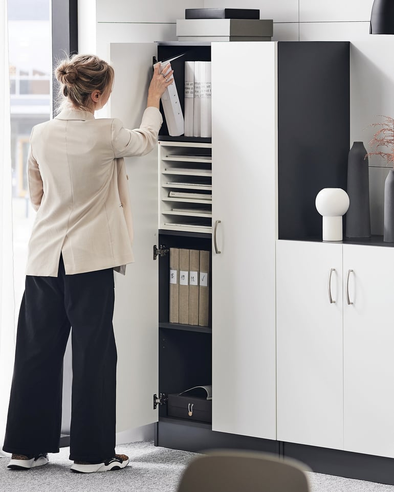 A woman storing items in office storage cabinets