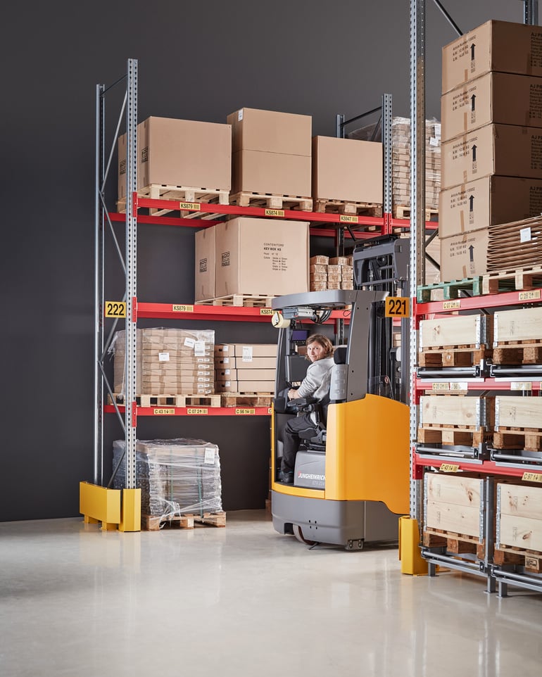 Warehouse worker operating a forklift in a warehouse with pallet racks