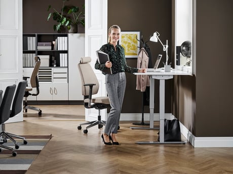 Žena v kanceláři stojí u výškově nastavitelného stolu