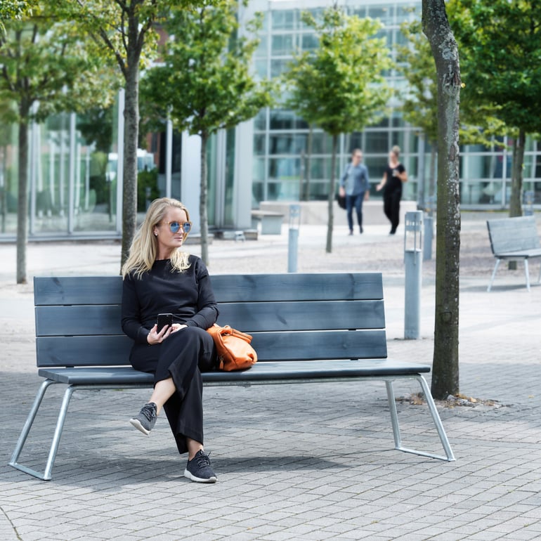 Kvinde sidder på en havebænk i en park 