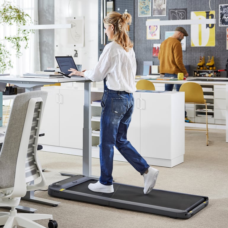 Woman walking on a treadmill while working at  a desk