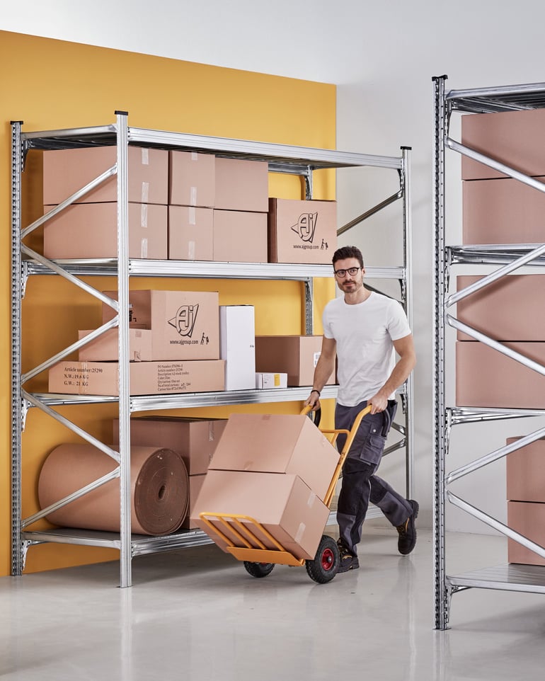 En lagerarbetare transporterar lådor på en magasinskärra