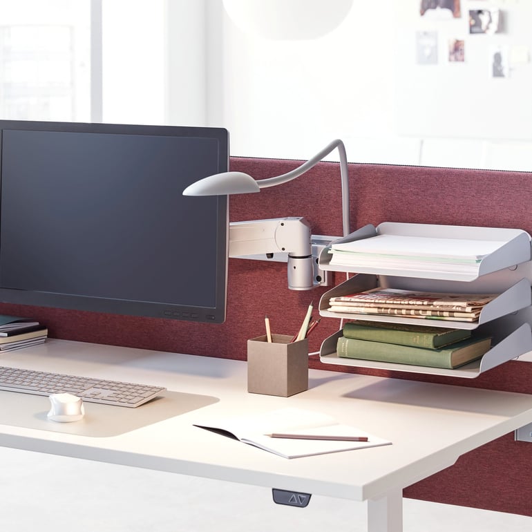 En lampa med böjbar arm fäst vid en skrivbordsskärm med funktionslist