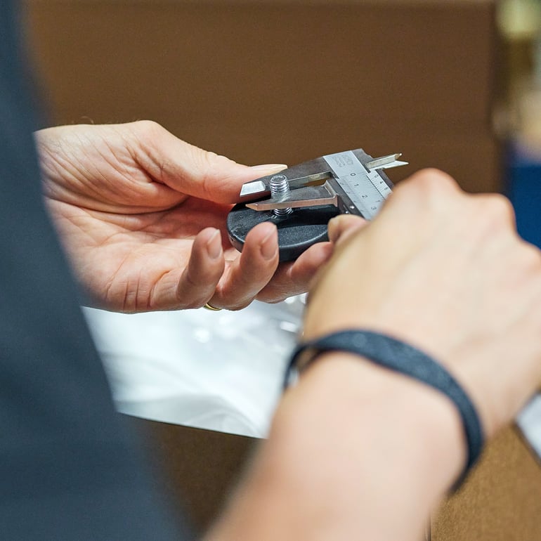 Person checking thread diameter on a screw