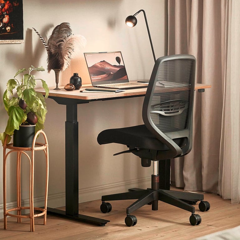 Sit-stand desk  with lamp and office chair in a home office