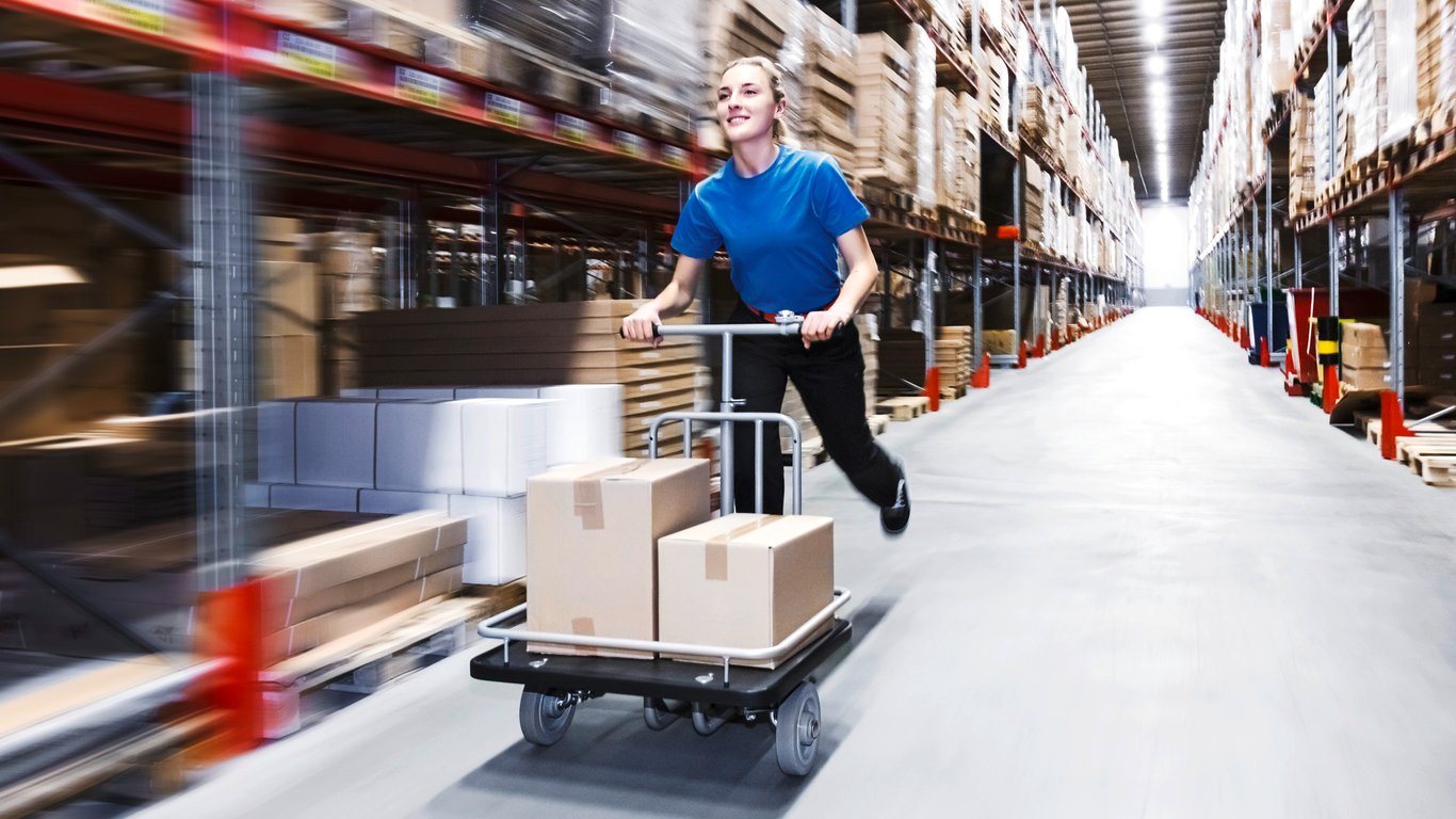 Person using platform trolley in a warehouse aisle