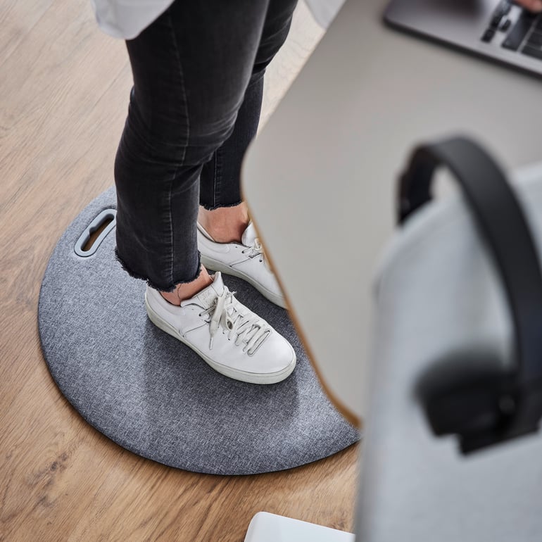 Person standing at a desk on a standing desk mat