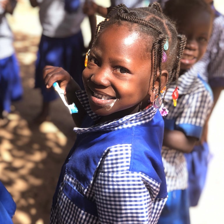 Young girl wearing scholl uniform and brushing her teeth