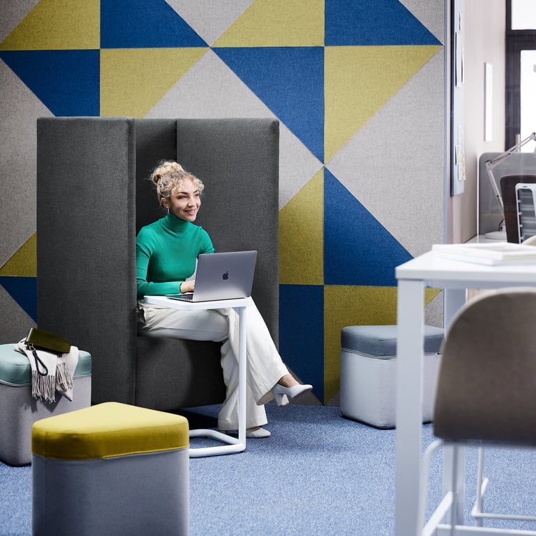 Ženska sedi na akustičnem kavču z visokimi stranicami v pisarni