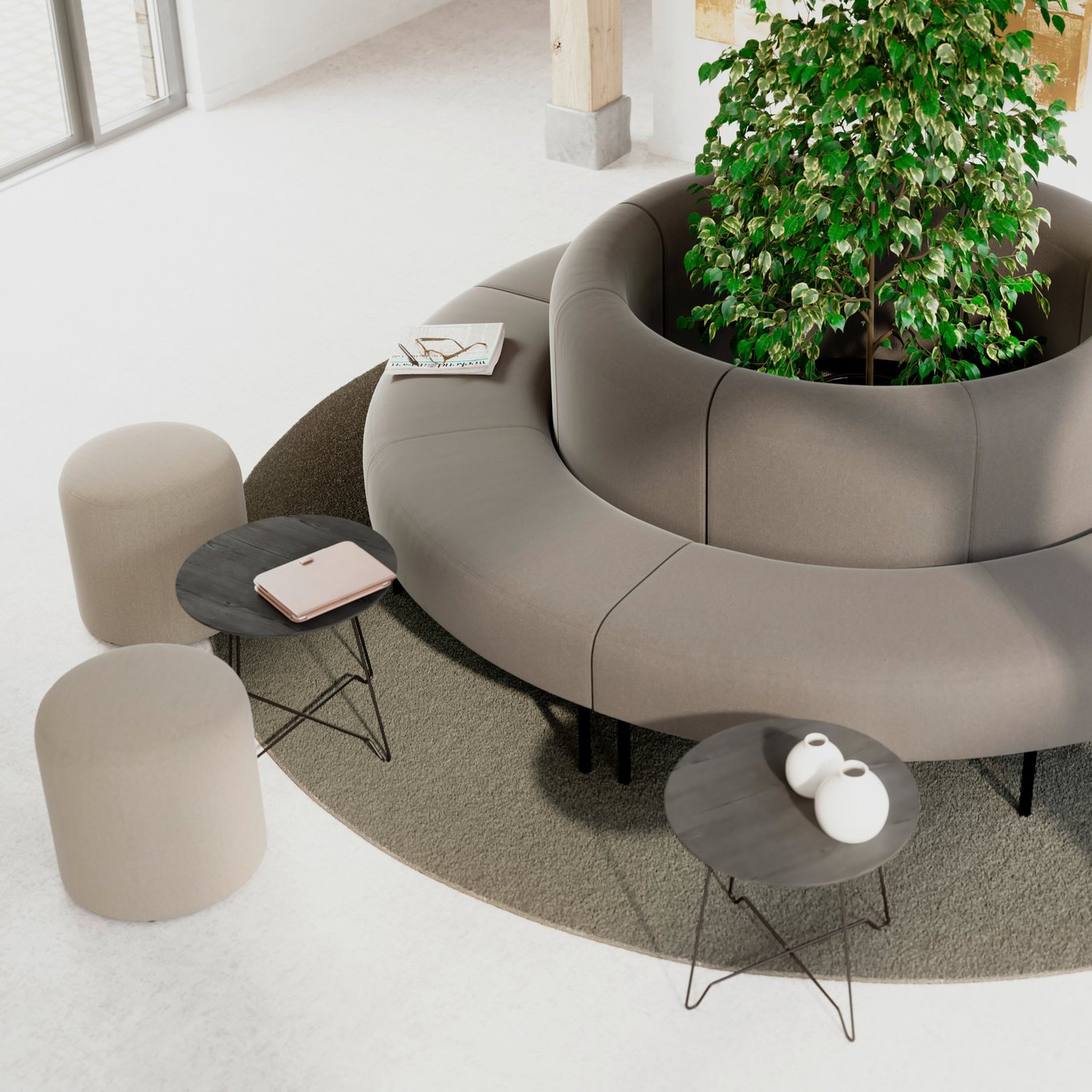 A grey circular sofa with plants in the middle