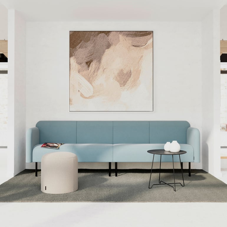 Blue sofa against a wall with a beige pouffe and black coffee table