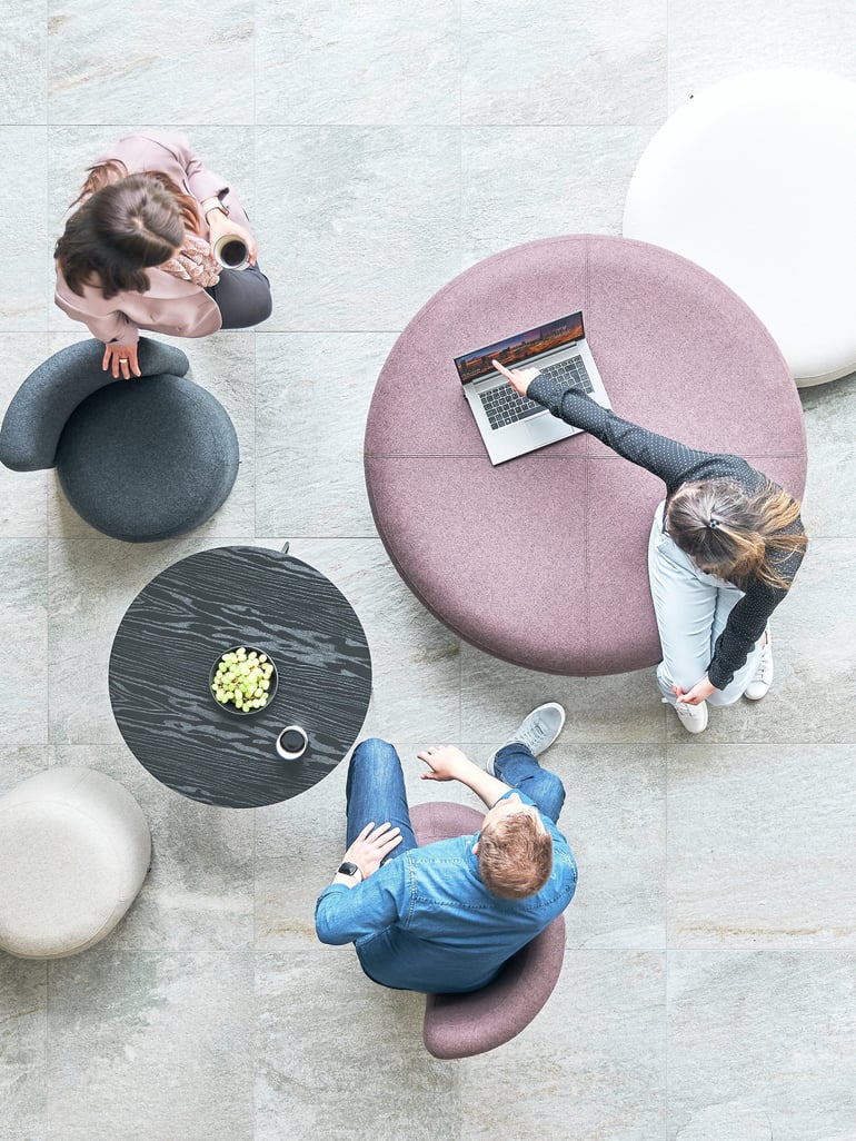Three people sitting and working in a breakout area with large round seats
